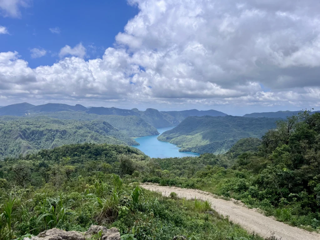 Laguna Brava seen from a dirt road winding through the green hills of Huehuetenango