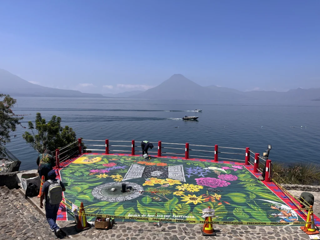 Artists finishing a coloured sawdust carpet on the shore of Lake Atitlán at Panajachel