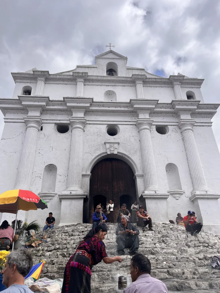 Vendors and visitors on the steps of a white colonial church in the Guatemalan highlands
