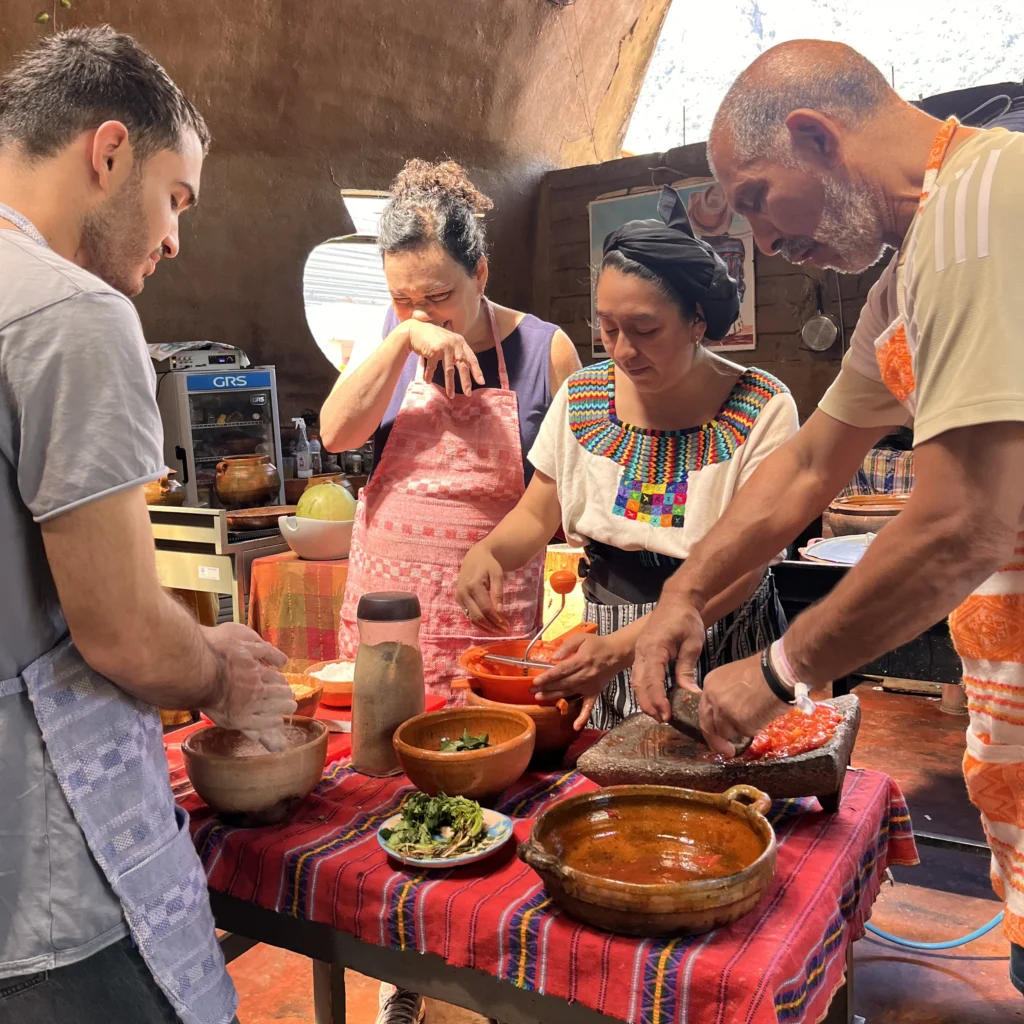 Travellers grinding tomatoes on a stone metate during a Guatemalan cooking class