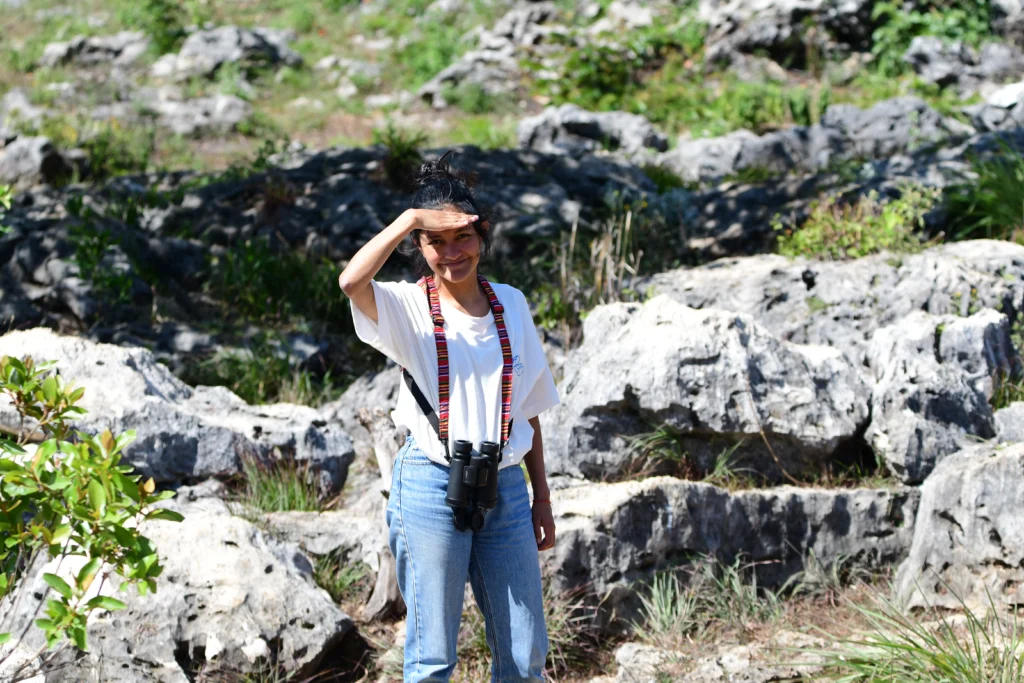Andrid Ramírez with binoculars, on the limestone rocks at Hoyo Cimarrón